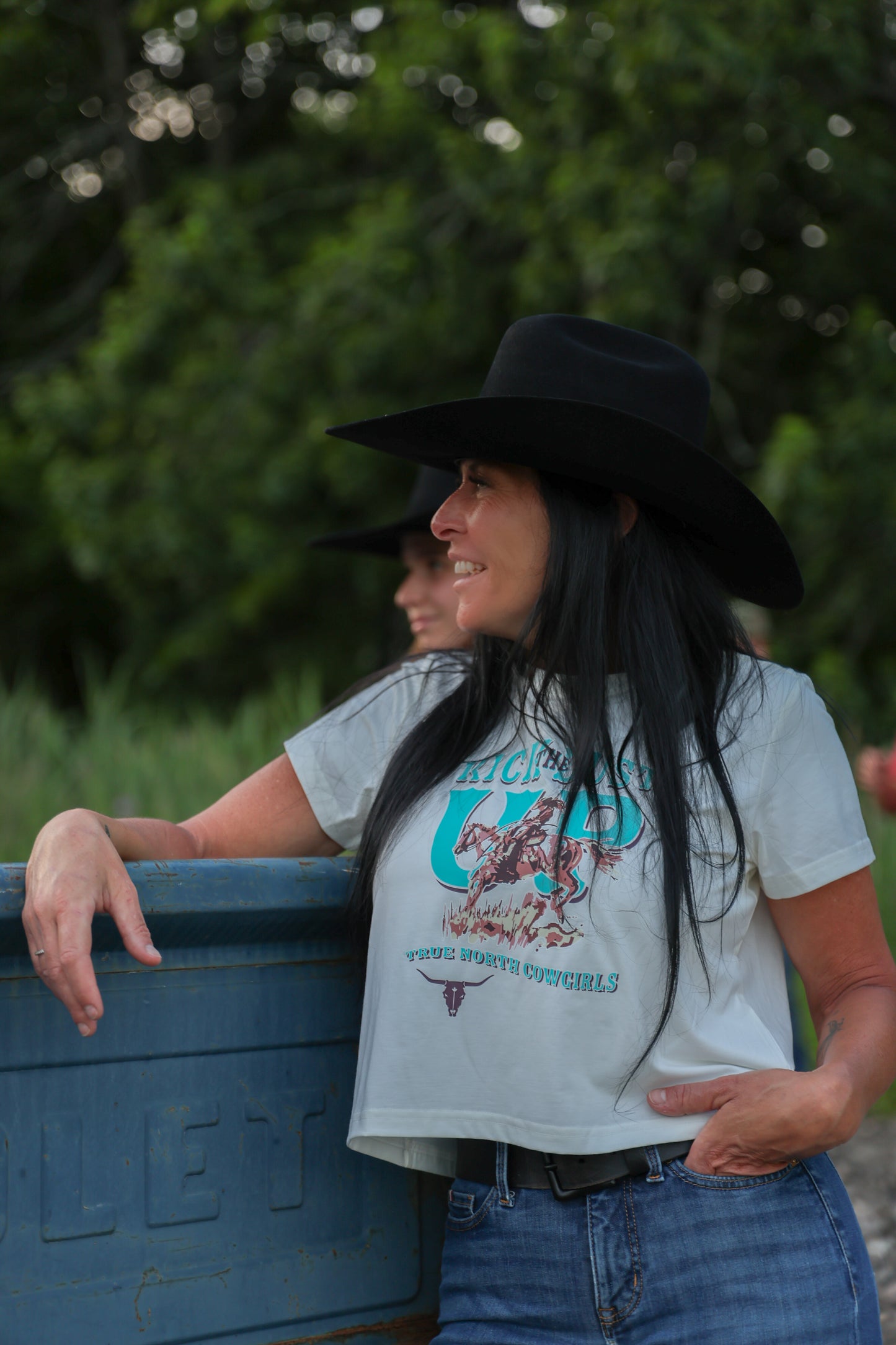 Woman wearing the white Shack Story Kick The Dust cropped T-shirt outdoors