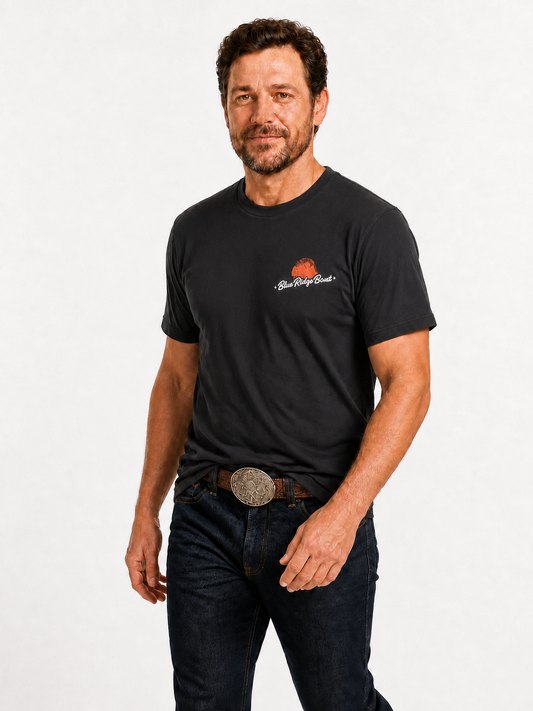 Man wearing the black Shack Story x Blue Ridge Band unisex T-shirt with western jeans and belt buckle, front view